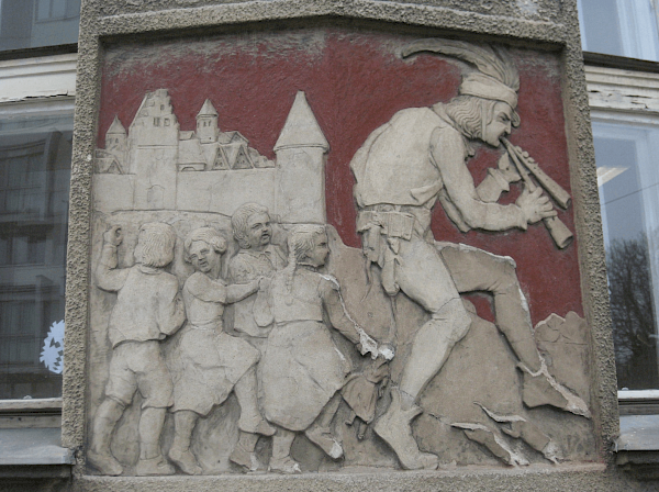 Darstellung des Rattenfängers von Hameln auf einer Steintafel mit rot bemaltem Hintergrund