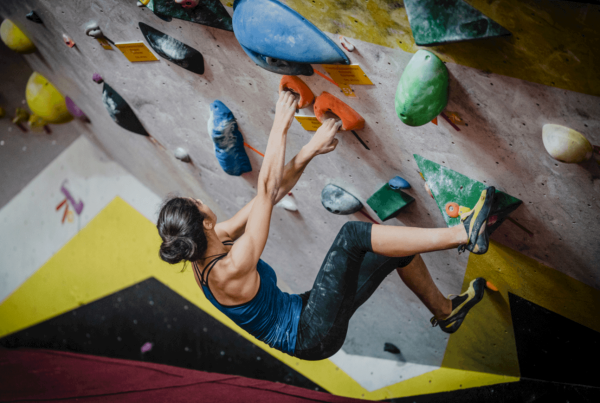 Junge Frau klettert in einer Boulderhalle ohne Gurt oder Seil
