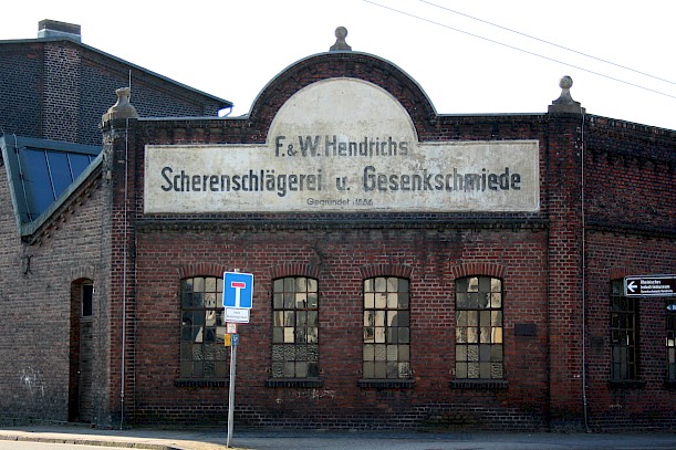 Firmengebäude der Gesenkschmiede Hendrichs mit großem Schild und vier alten Fenstern an der Front.